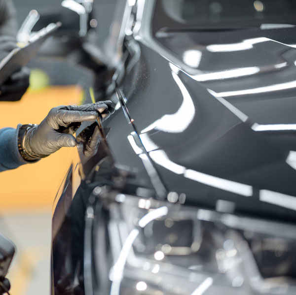 Master technician performing quality inspection on a vehicle after paintless dent repair.
